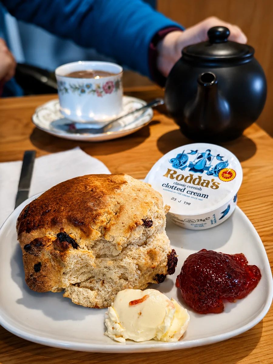 Tea and a fruit scone served with clotted cream and strawberry jam